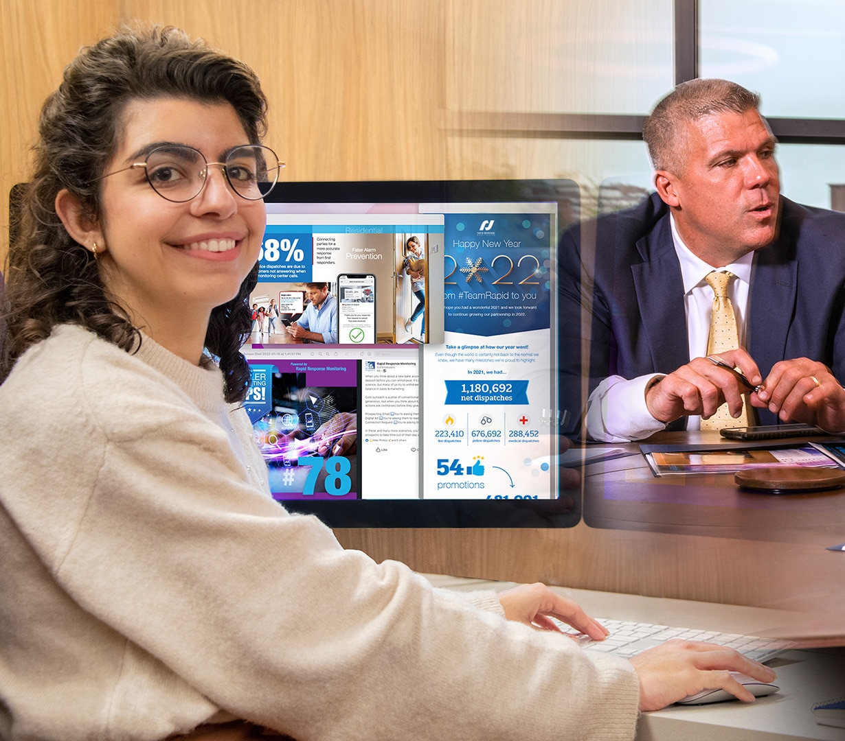 Woman smiling in front of computer with man at desk in background.