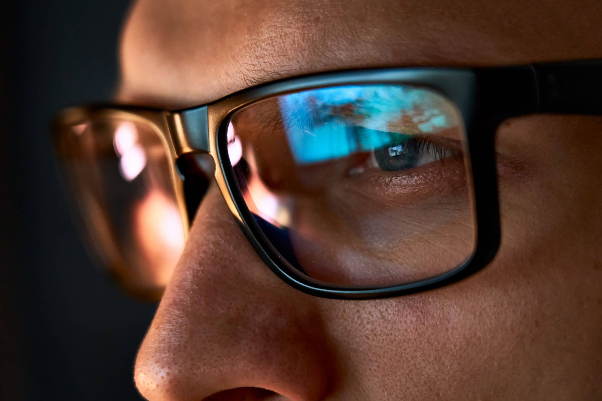 Close up of man wearing glasses looking at computer screen.