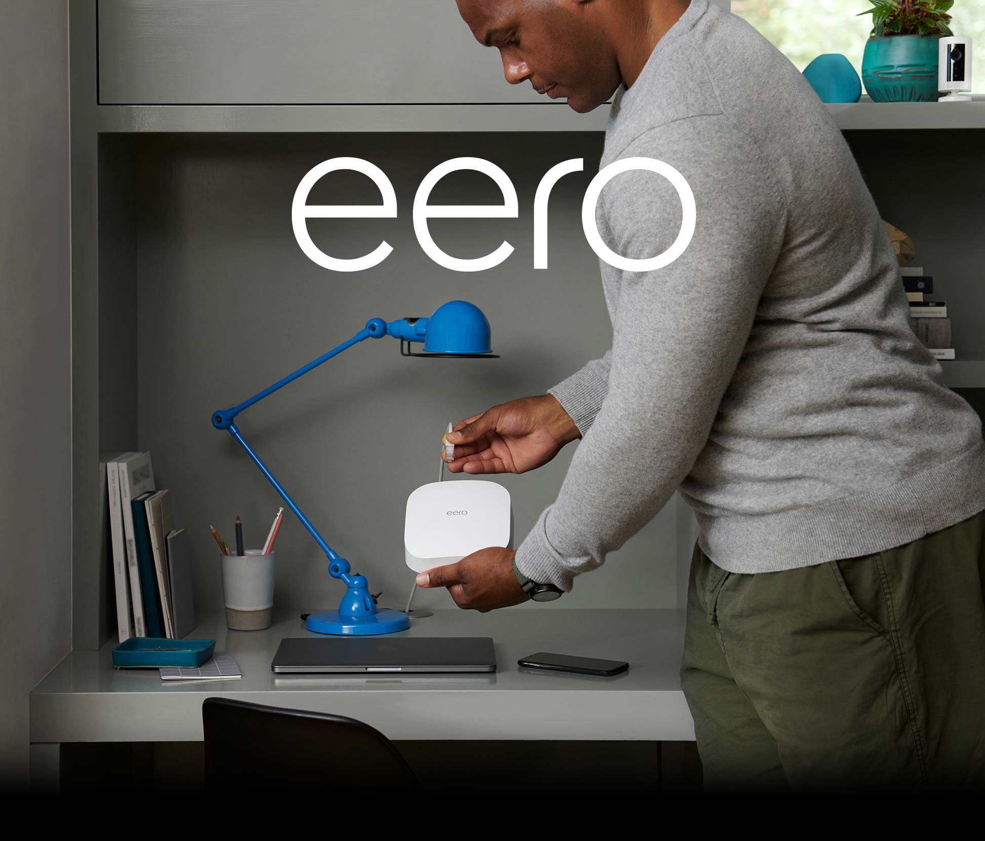 An image of a guy plugging in an electronic with the words "eero"